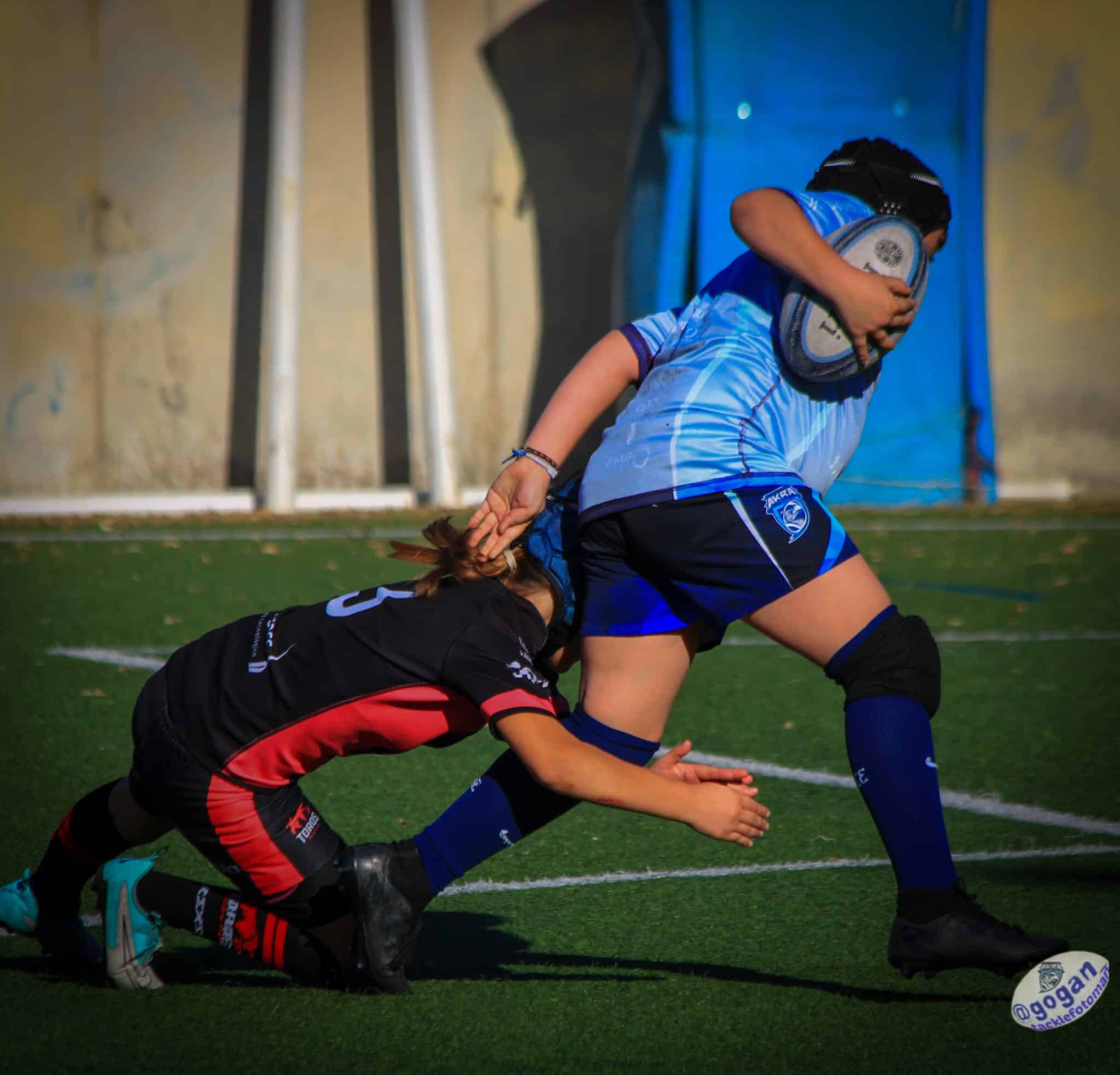 Acción de placaje en rugby base durante un partido entre dos jugadoras
